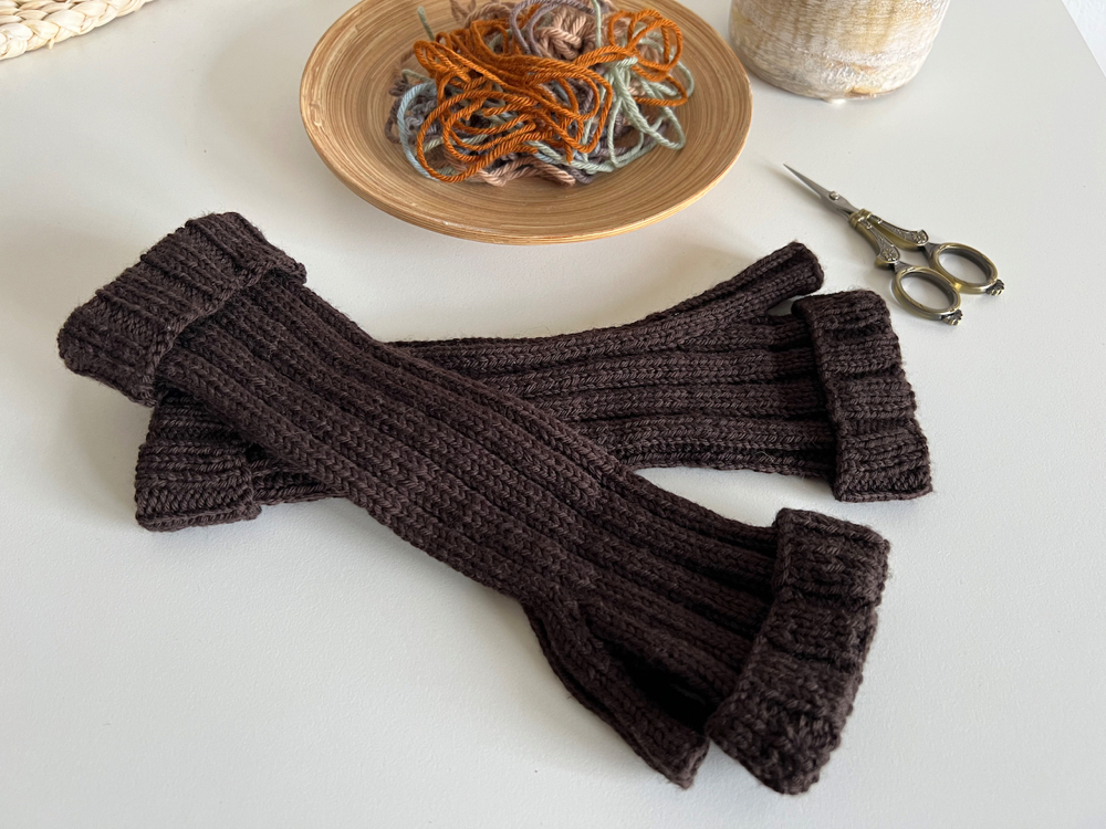 Coffee brown hand cuffs on a table with wool remnants and small scissors