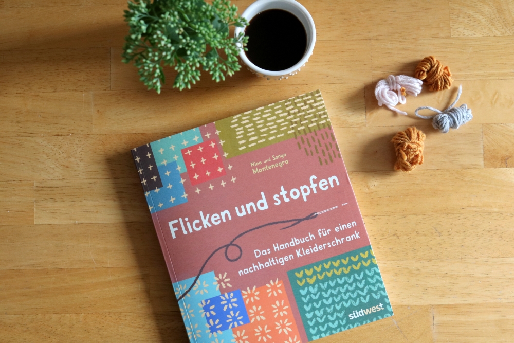Left-over yarns and a book titled Flicken und stopfen (Mending and darning) on a table.