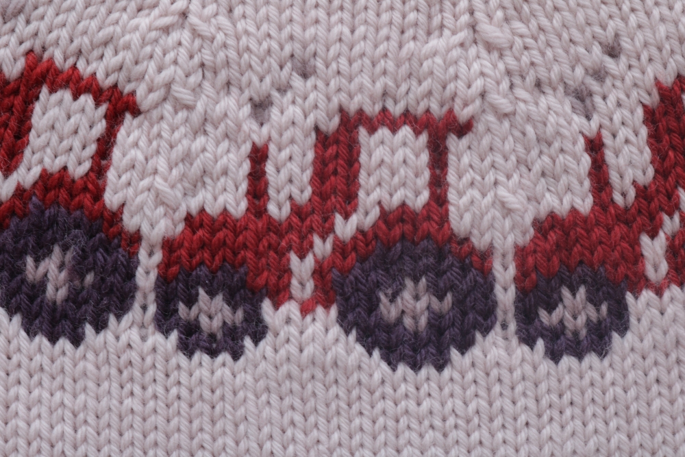 Knitting pattern of colourful tractors on a cream background